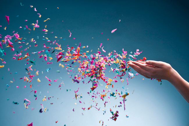 A hand with confetti flying out of it